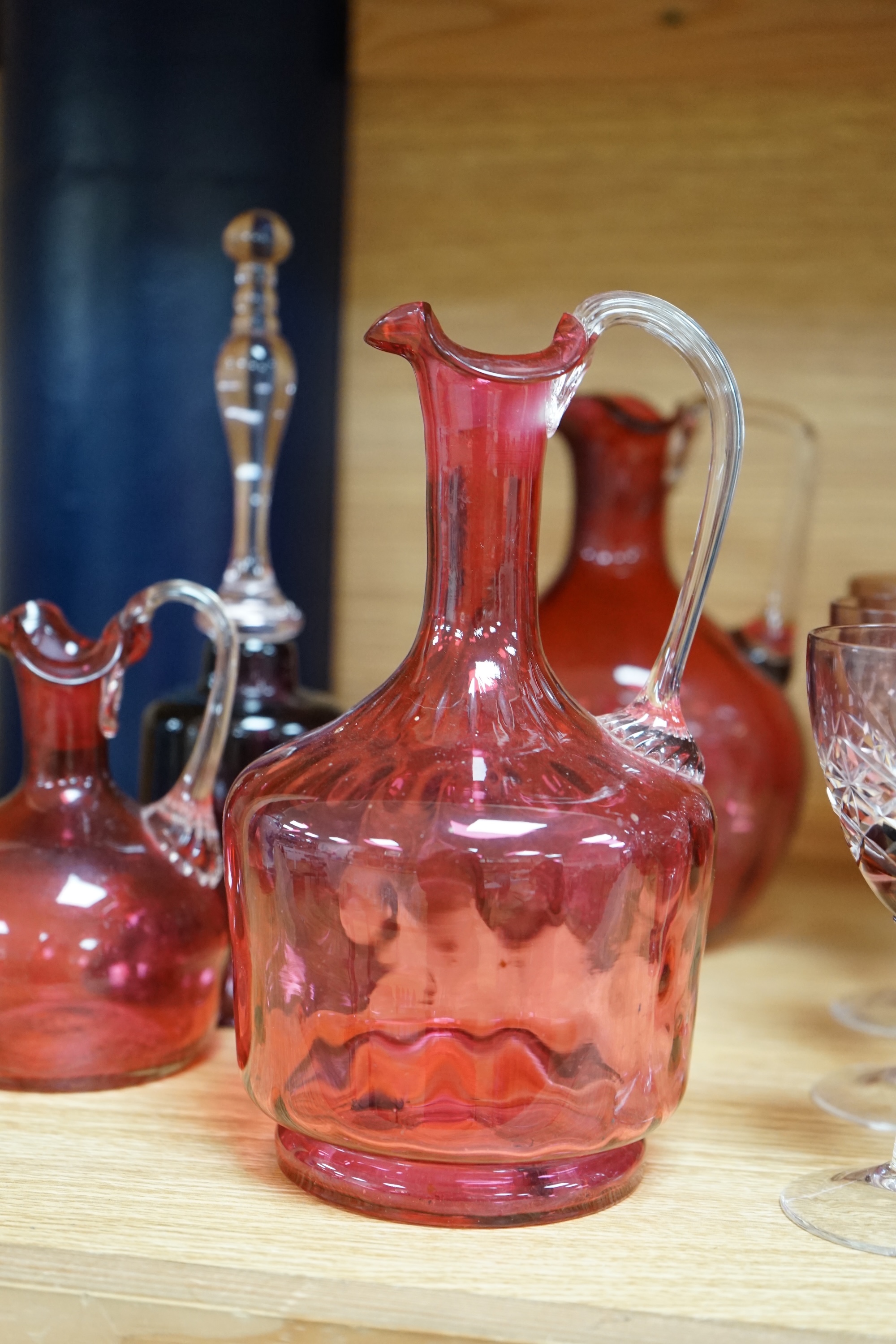 Mixed cranberry glassware to include jugs, glasses, jars and a comport, largest 23cm high. Condition - fair to good